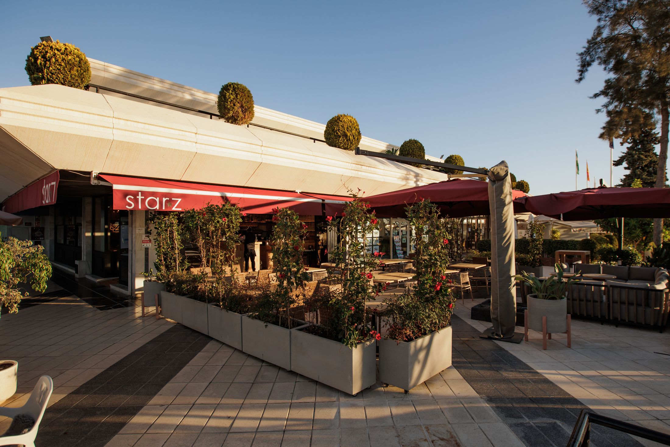 The Starz terrace in Centro Plaza, Nueva Andalucía, under its red awnings in the late afternoon sun